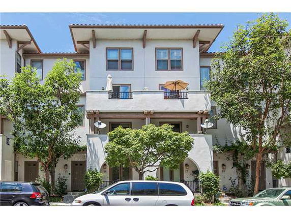 Front view of a three-story townhouse with balconies and arches.