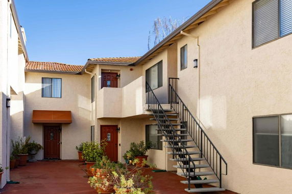 Exterior view of a two-story apartment building with exterior staircases and doorways.