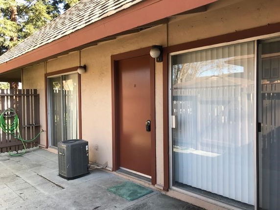 Front view of a building with sliding glass doors and a brown entry door.