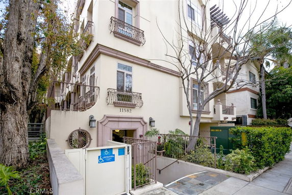 Front view of a multi-story residential building with balconies and a gated entrance.