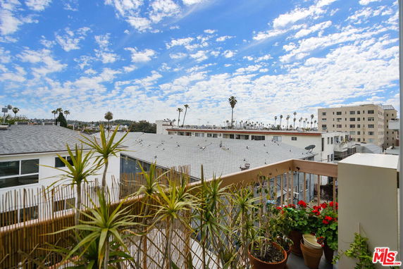 View from a building balcony overlooking rooftops and distant buildings.