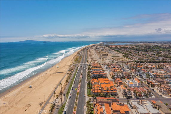 Panoramic view of a coastal area with a road, beach, and buildings along the shoreline.