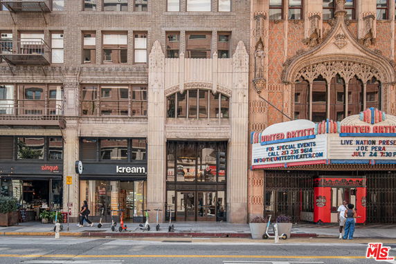 Front view of a multi-story commercial building with shops and a theater entrance.