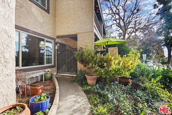 Front view of a residential building entrance with plants and a gate.