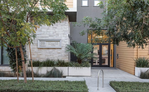 Front view of a modern building entrance with stone and wooden exterior finish.