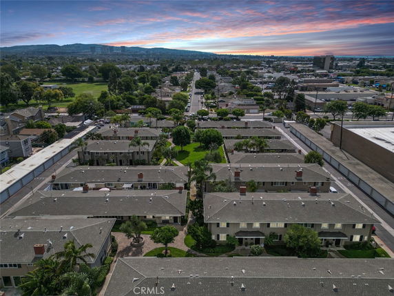 Panoramic view of residential buildings and surroundings, with a sunset in the background.