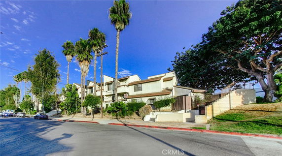 Front view of a multi-story residential building with palm trees.