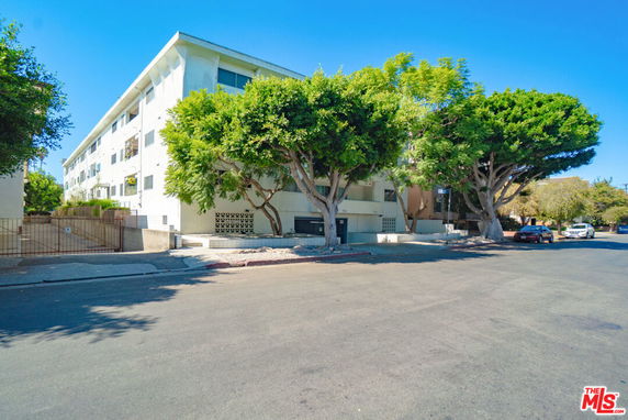 Front view of a multi-story residential building with trees in front.