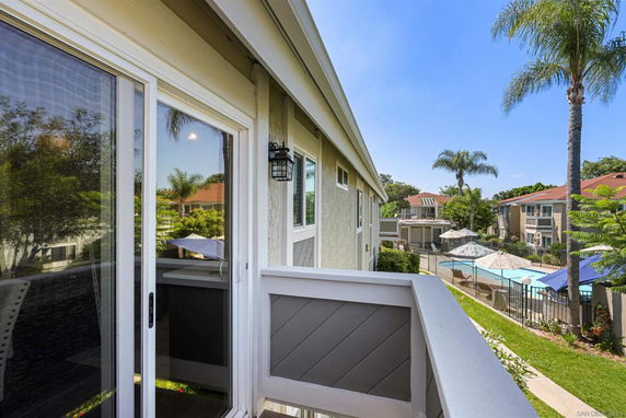 View from a balcony overlooking a residential area with a swimming pool and palm trees.