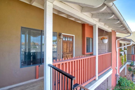 Front view of a house with a wooden door and balcony railing.