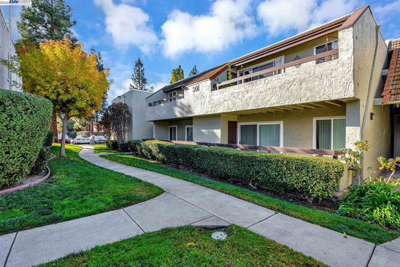 Front view of a two-story building with balconies and landscaped surroundings.