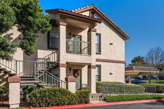 Front view of a two-story house with exterior stairs and a small balcony.