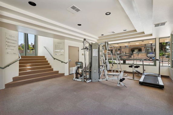 Indoor gym area with exercise equipment including a treadmill and weight machine.