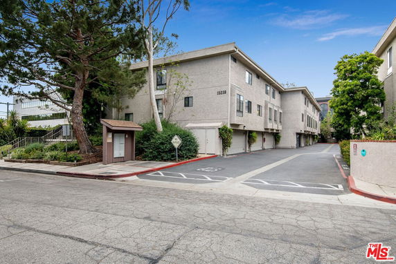 Front view of a multi-story apartment building with a parking area.