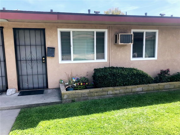 Front view of a single-story house with metal security door and window-mounted air conditioner.