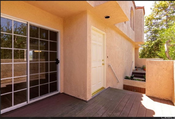 Front view of a house with a sliding glass door and a wooden entryway.