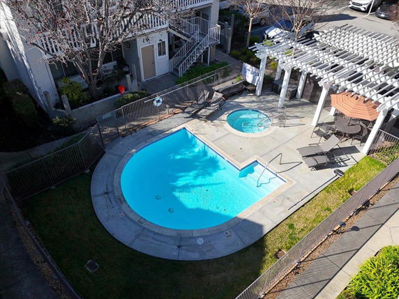 Outdoor area with a swimming pool and a hot tub surrounded by a fenced enclosure.