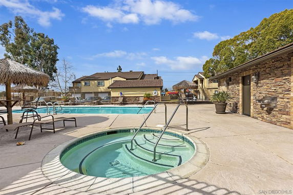 Outdoor swimming pool area with a spa and lounge chairs.