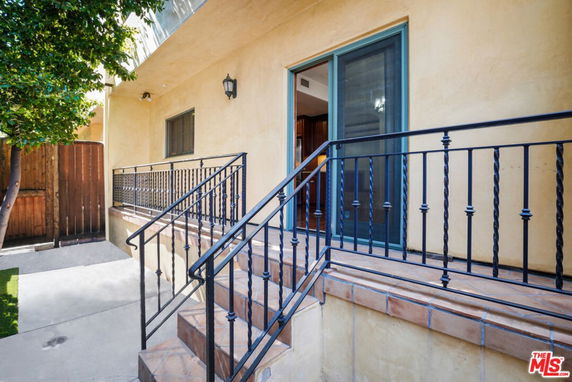 View of a house entrance with steps and metal railing.