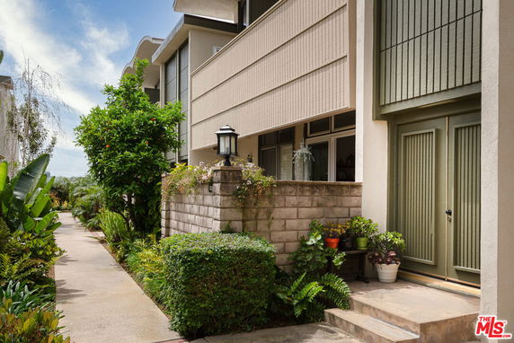 Front view of a modern, multi-story building with a garden path and plants.
