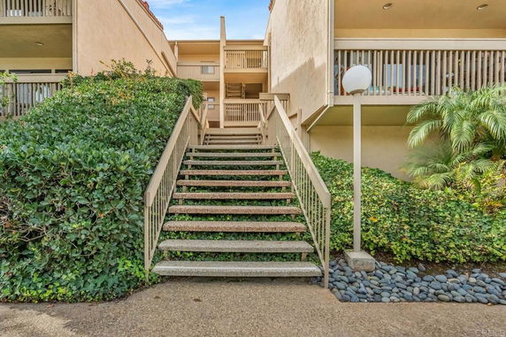 Stairway leading to the entrance of a multi-level building with balconies.