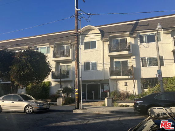 Front view of a three-story building with balconies and entrance.