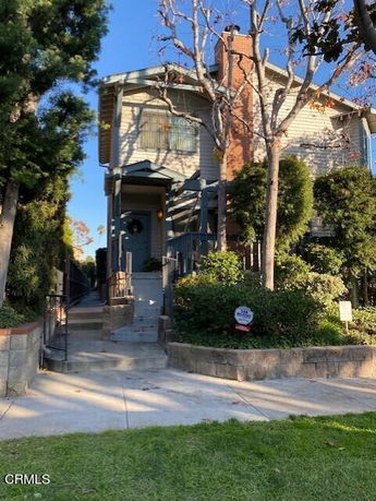 Front view of a two-story house with a chimney and a small front yard.