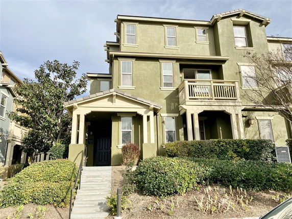 Front view of a three-story house with a porch and balcony.