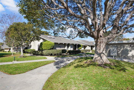 Front view of a house with a large tree and pathway.