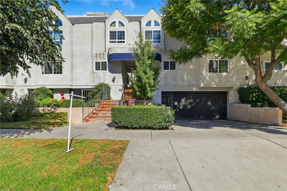Front view of a multi-story residential building with arched windows and a garage.