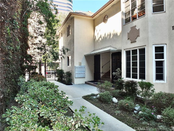 Front view of a two-story residential building with a pathway and entrance.