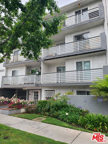 Front view of a multi-story building with balconies and a landscaped entrance.