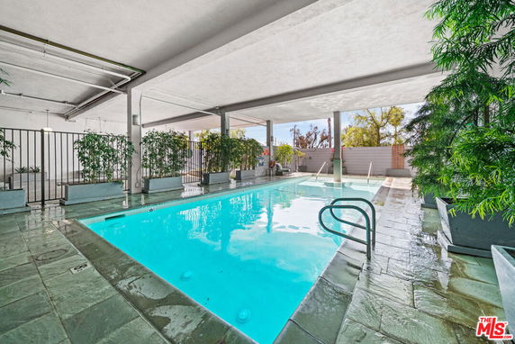 Covered outdoor swimming pool area with surrounding plants.