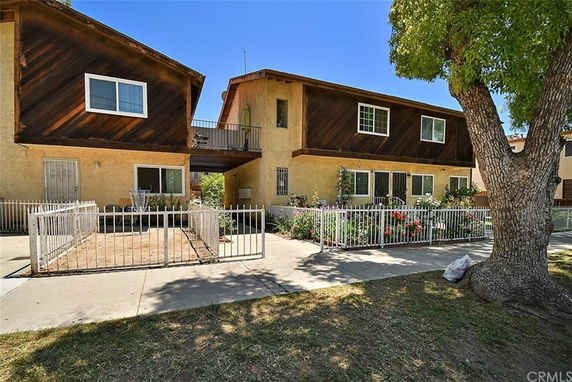 Front view of a two-story residential building with a fenced yard.