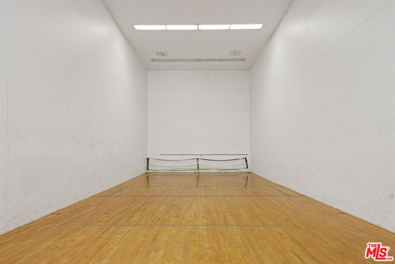 Indoor racquetball or squash court with a wooden floor and white walls.