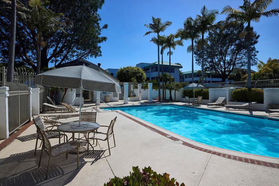 Outdoor swimming pool area with lounge chairs and umbrellas.