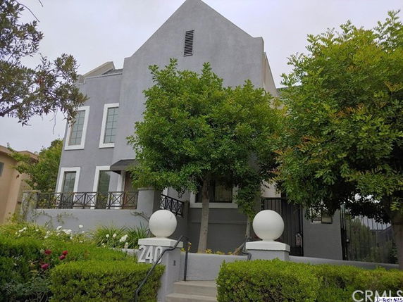 Front view of a multi-story house with a gray exterior and gated entrance.