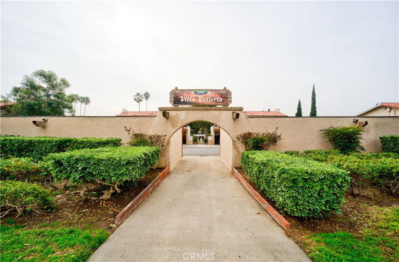 Entrance view of a building with an archway and surrounding greenery.