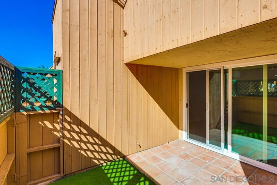 Exterior corner view of a building with sliding glass doors and a wooden fence on a rooftop area.