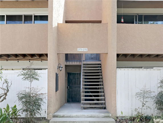 Front view of a multi-story building with external staircase and entrance.