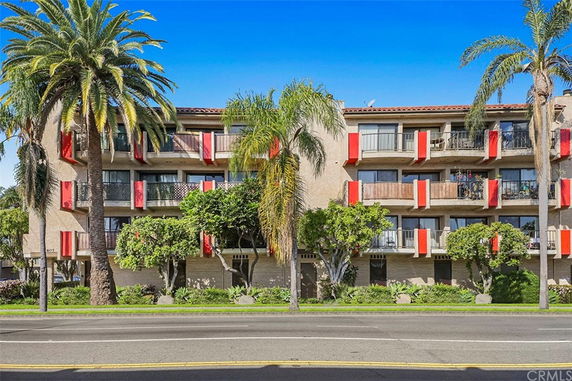 Front view of a multi-story apartment building with balconies and red accents.