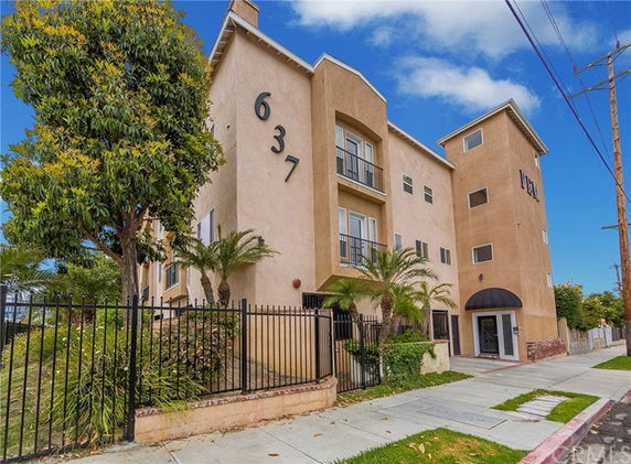 Front view of a multi-story apartment building with balconies and large numbers on the facade.