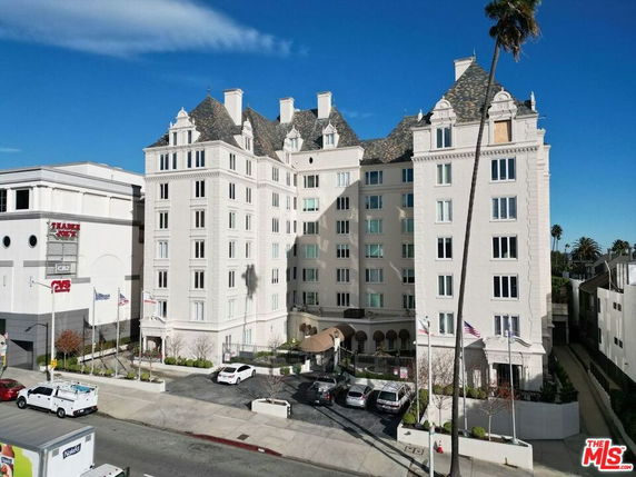 Front view of a multi-story building with a detailed roof and multiple windows.