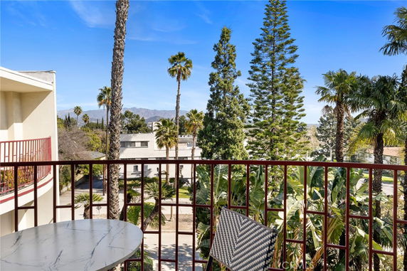 Outdoor balcony view with nearby building and tall trees