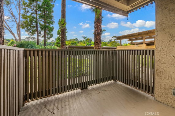 A small fenced outdoor area with a view of trees and a wooden structure.