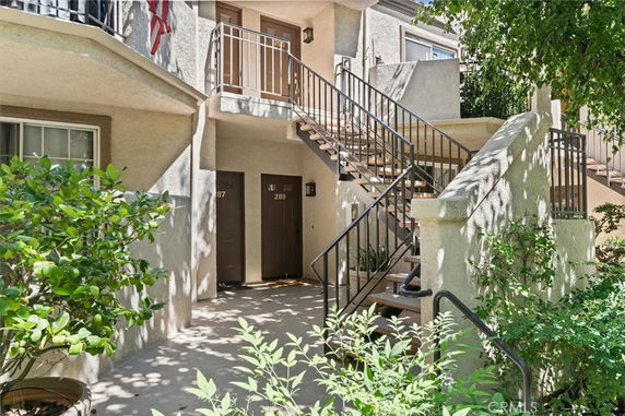 Front view of a multi-unit apartment complex with stairs leading to the upper level.