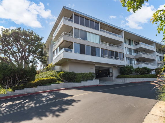 Front view of a multi-story apartment building with large balconies.