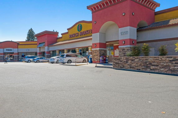 Front view of a commercial building with multiple storefronts and a parking area.