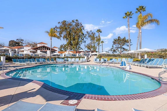 Outdoor swimming pool area with lounge chairs and umbrellas.