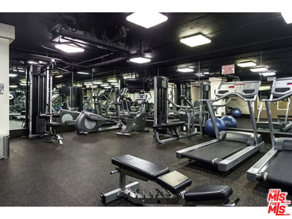 Interior view of a gym with exercise equipment including treadmills and weights.